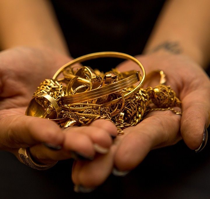 Mãos segurando peças de ouro para avaliação